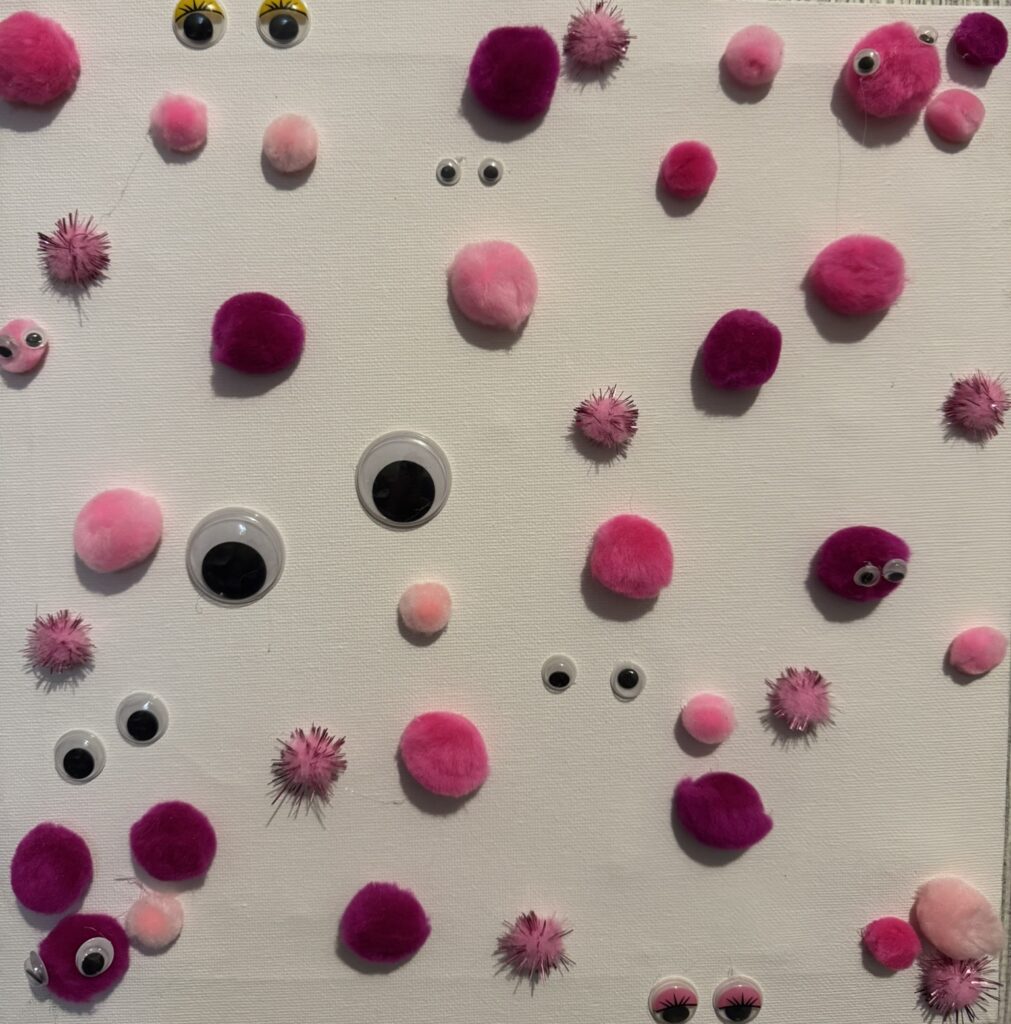 pompoms and googly eyes on a canvas